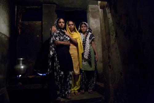 Tekstiilityöntekijöitä Bangladeshissa jakamansa huoneen edessä